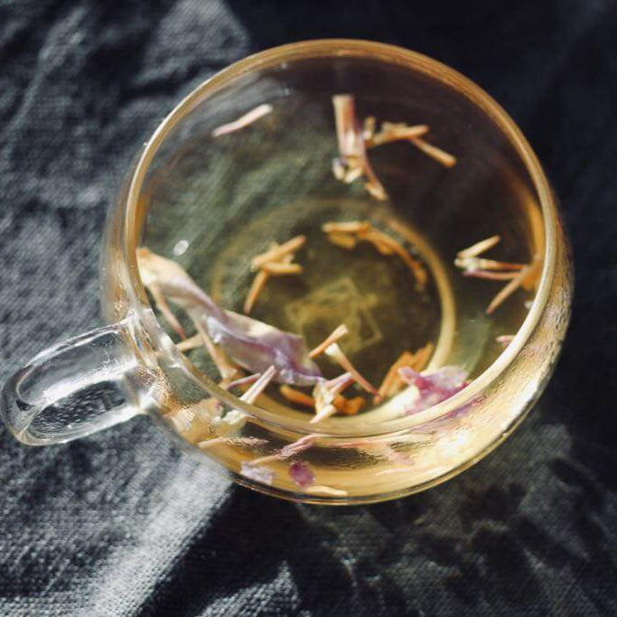 glass cup with blue lotus tea petals 