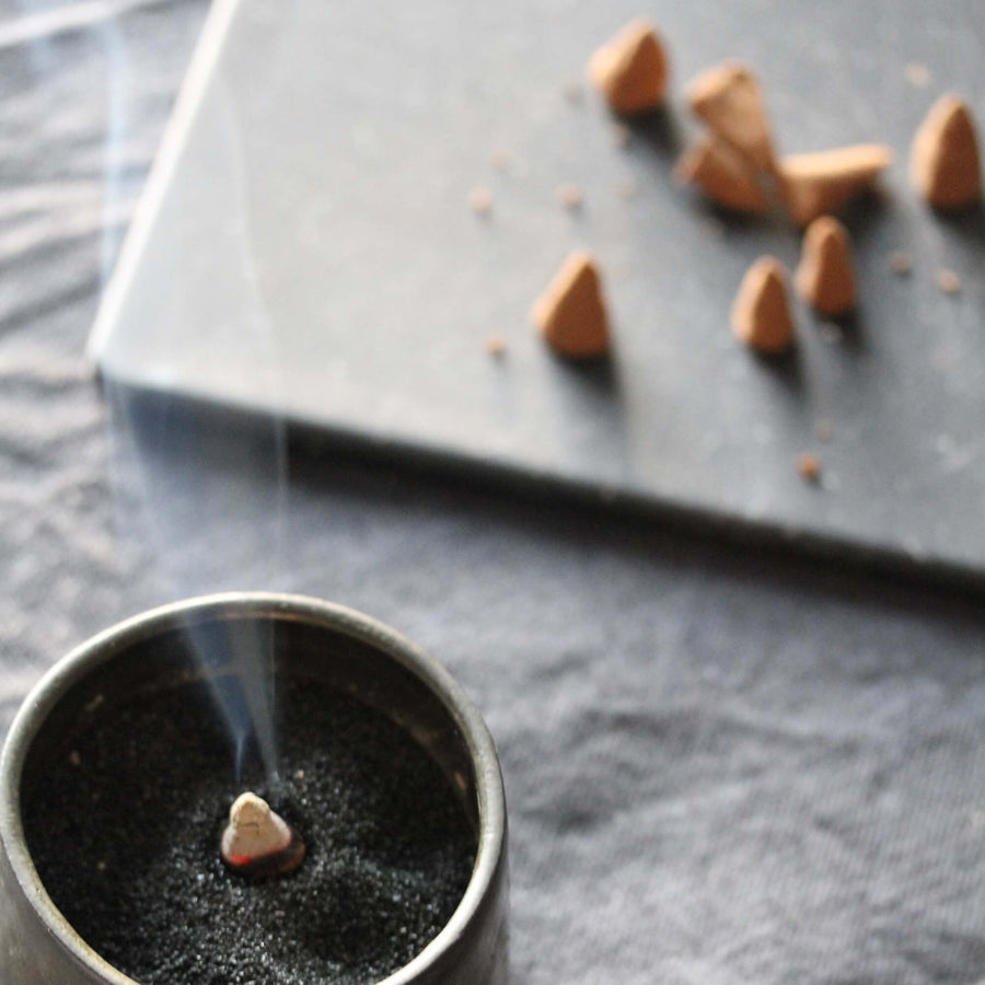 Incense burner with smoke on a dark surface